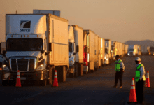 a man standing in front of a row of semi trucks