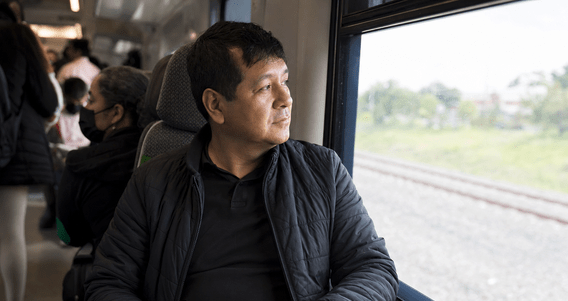 Pasajero mira por la ventana de un tren interurbano mientras sostiene su teléfono